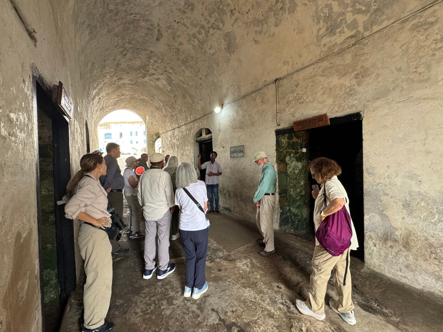Visitors in the vaulted dungeon corridor of Cape Coast Castle, Ghana