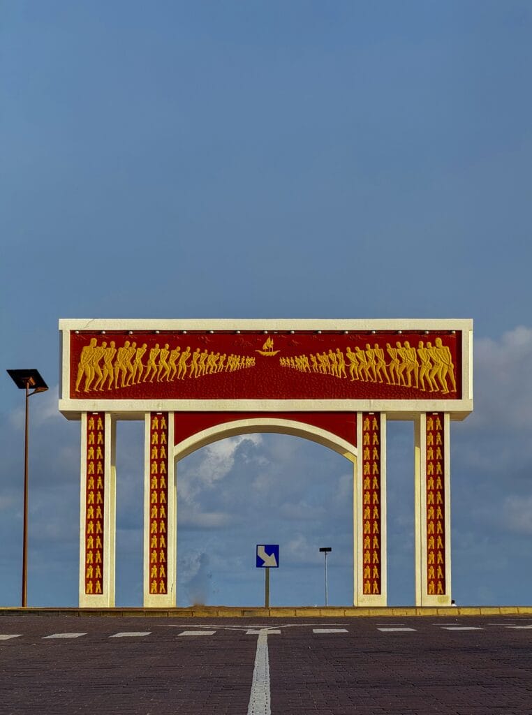 La Porte du Non-Retour d Ouidah, memorial de la traite negriere, bas-reliefs dores sur ciel bleu