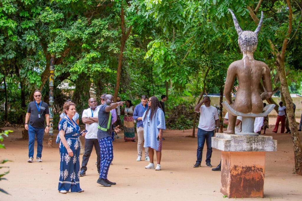 Statue de Legba dans la foret sacree de Kpasse a Ouidah, visiteurs autour