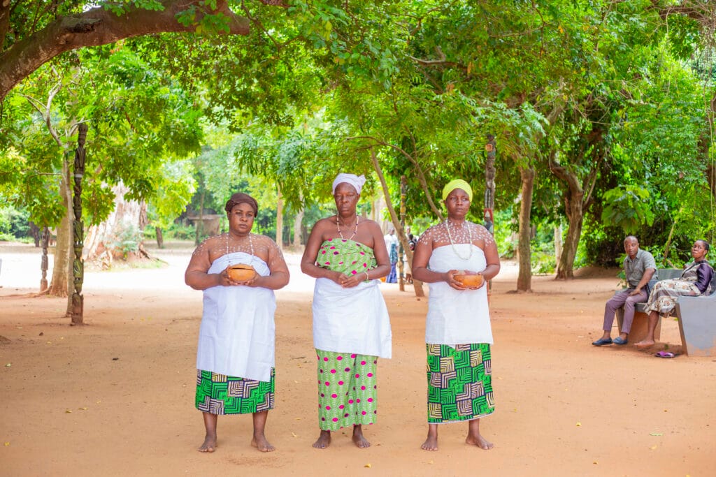 Trois vodunsi en tenue blanche dans la foret sacree de Kpasse a Ouidah