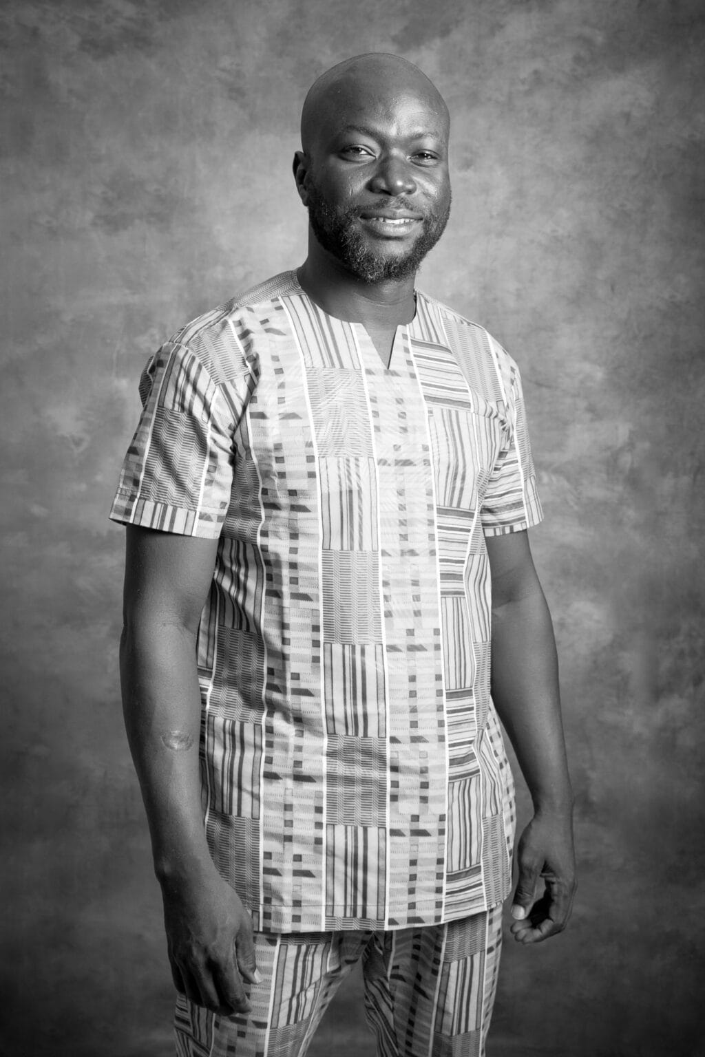 Oluwafemi (Fèmi) Kochoni, founder of Heritage and Routes, black-and-white portrait in a kente tunic