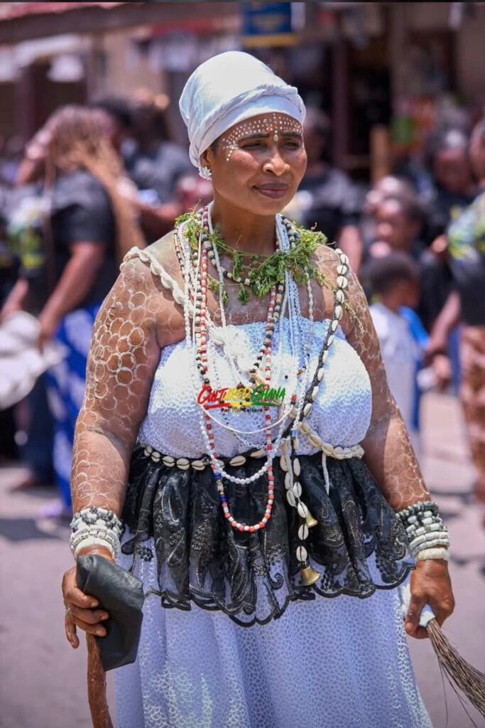 Traditional priestess in white cloth and headwrap, cowrie necklaces and white face marks, during Fetu Afahye in Cape Coast